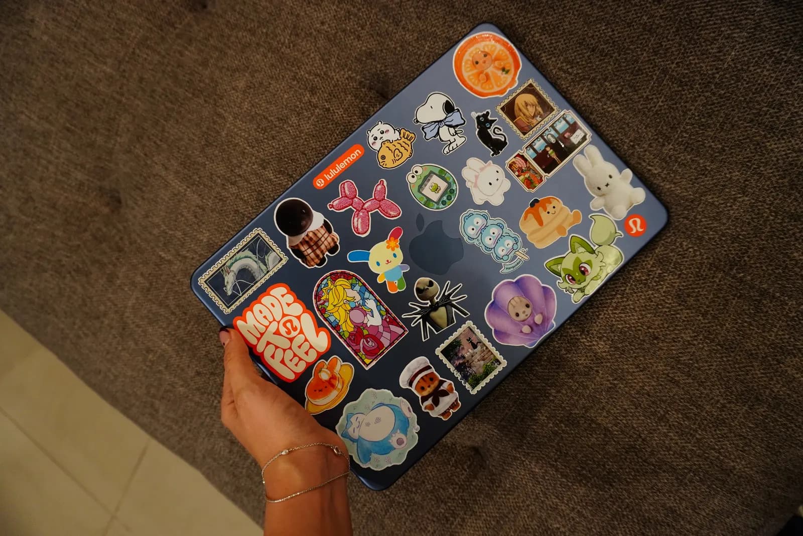 Vista superior de una laptop azul con decenas de stickers de vinil troquelados: personajes, estampillas y logos