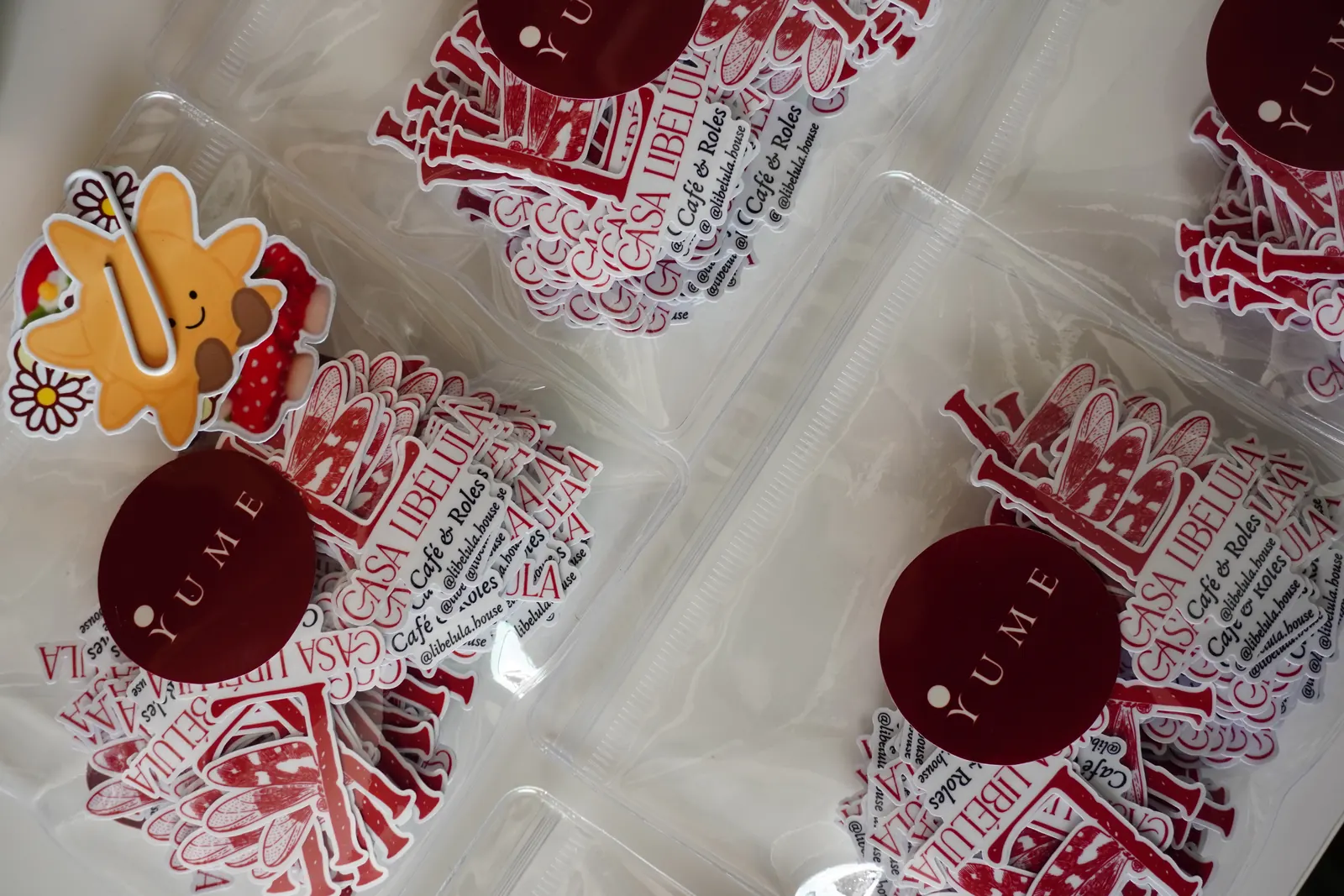 Bolsitas transparentes con stickers troquelados del logo de una cafetería de roles, cerradas con el sello redondo de Yume
