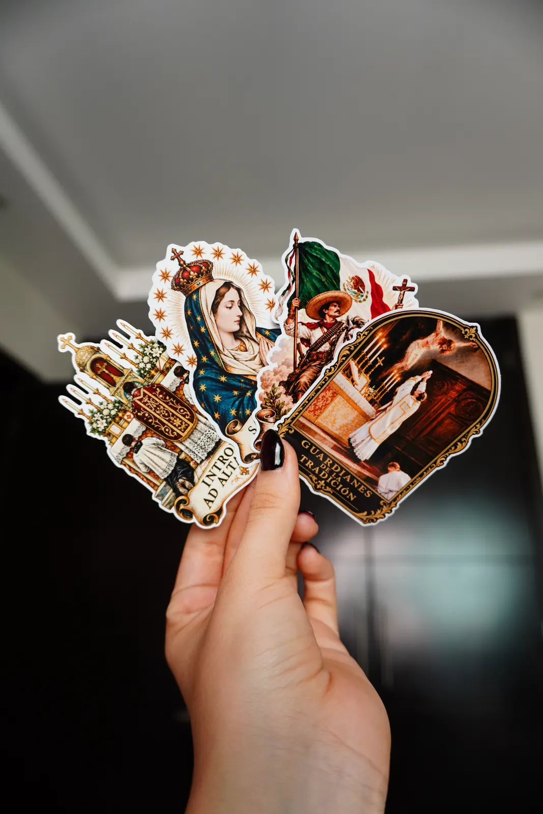 Mano sosteniendo stickers troquelados: Virgen María, ¡Viva Cristo Rey!, Introibo ad altare Dei y Guardianes de la Tradición