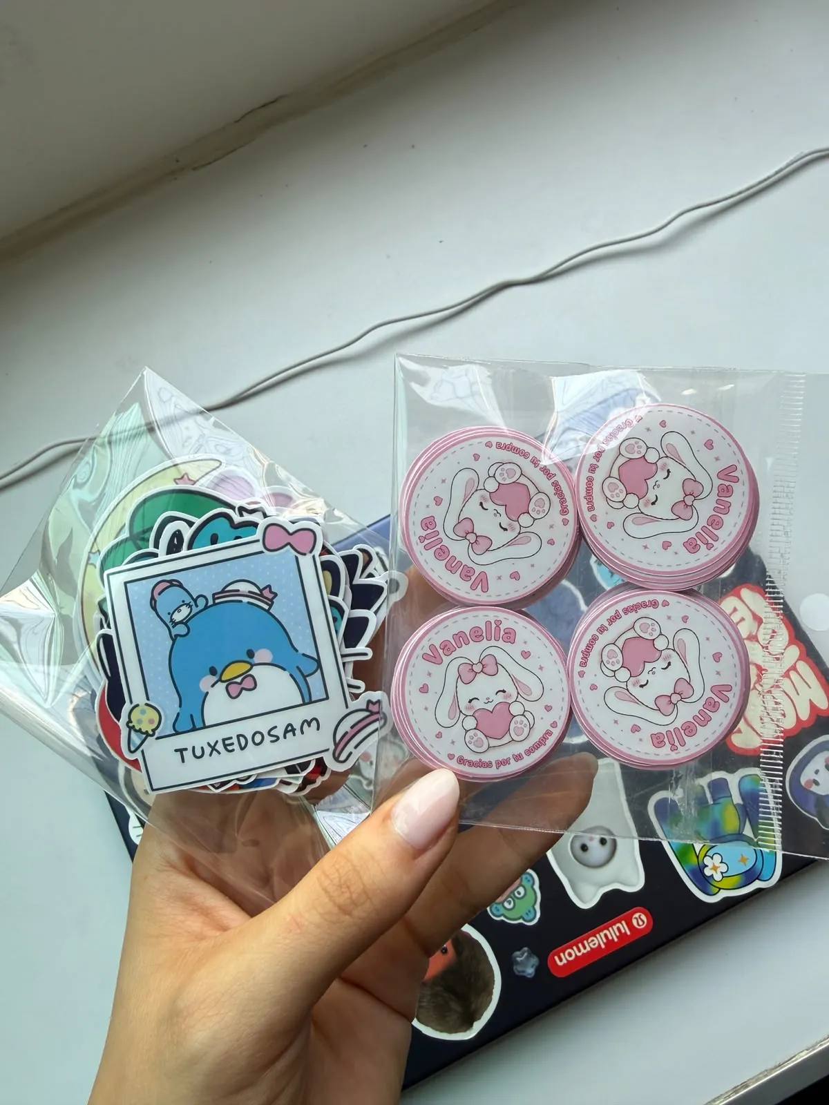 Bag of Tuxedosam stickers next to circular stickers for the custom Vanelia logo