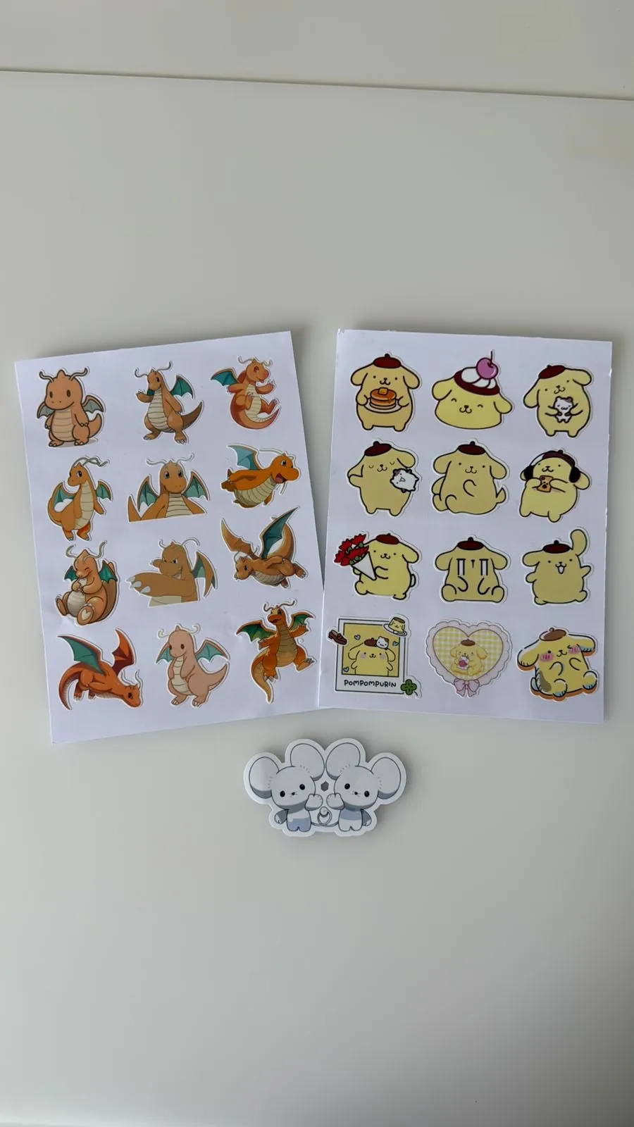 Sheet of Dragonite evolution-line stickers next to a Pompompurin sheet, on vinyl